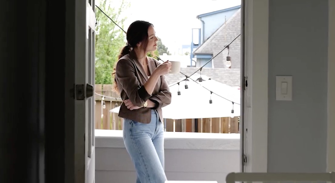 Hannah pausing with coffee at a home's doorway